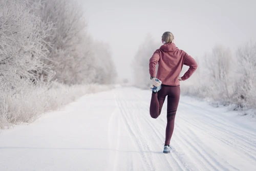 Fitness woman runner on sunny winter road