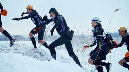 Group of swimmers running up from icy lake.