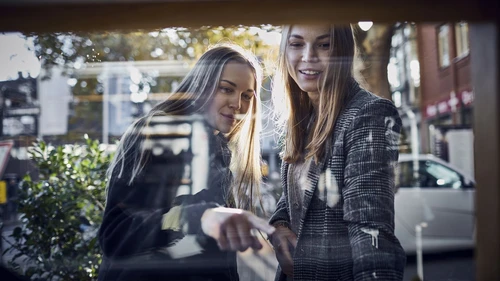 two-young-women-looking-through-shop-window
