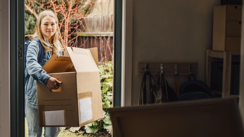 Young woman entering house with moving boxes