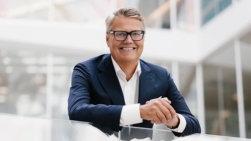 Man i kostym står i en trappa med glasräcken.