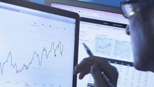 Financial services, stock analyst researching share price data of a company on the computer