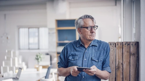 Senior man standing and holding a tablet