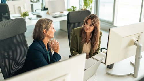 Two female colleagues discussing the working plan in front of their computer