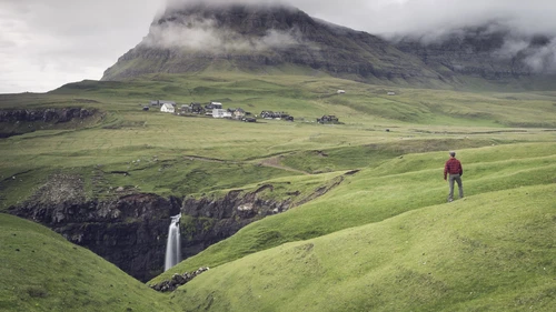 Man admires the little village of Gasadalur, Vagar Island, Faroe Islands, Denmark, Europe
