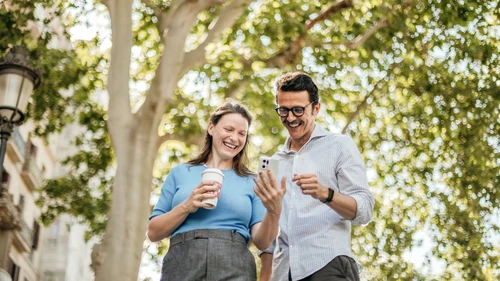 Woman and man checking phone outdoors. 