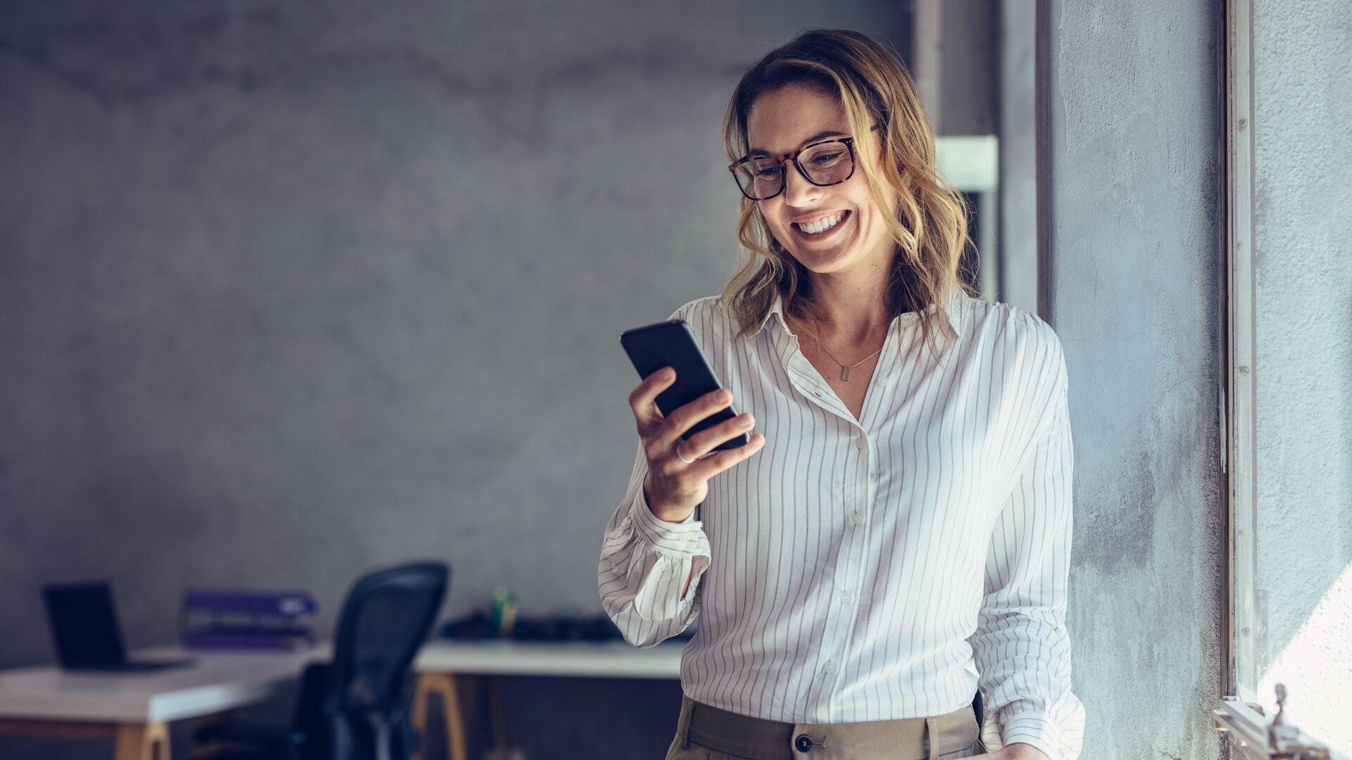 Smiling businesswoman using phone in office