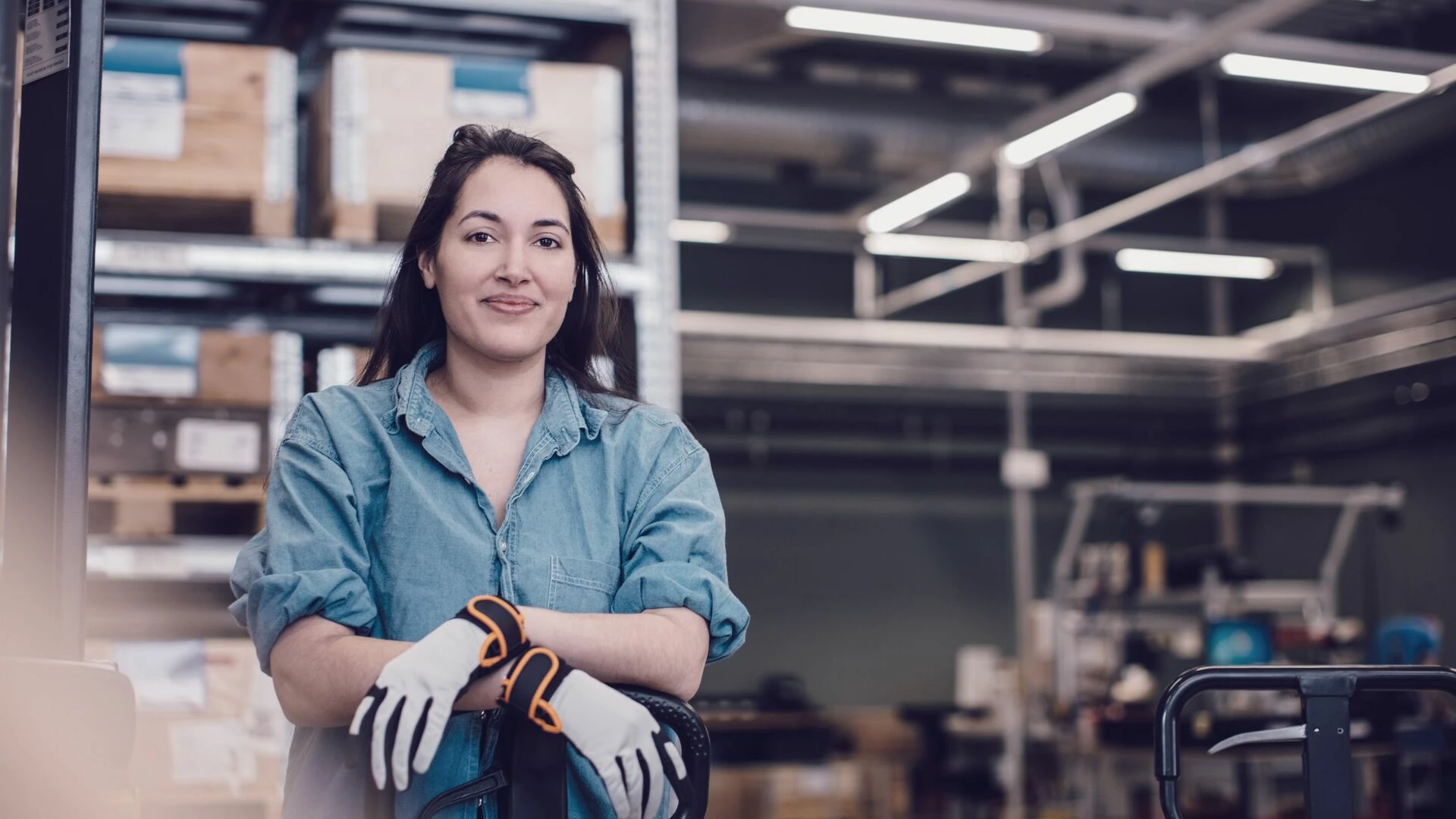 Young worker leaning on pallet jack at warehouse