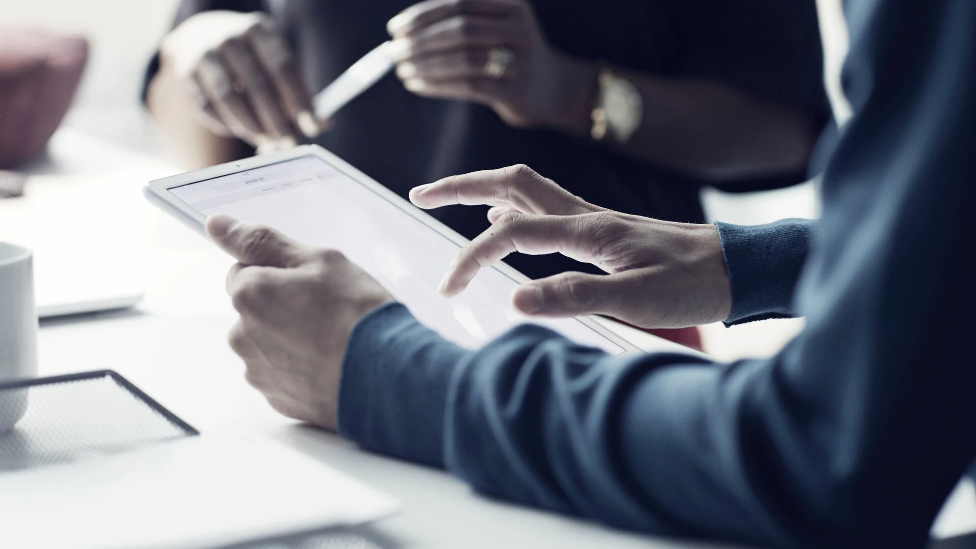 Close-up of co-workers standing at desk with laptop