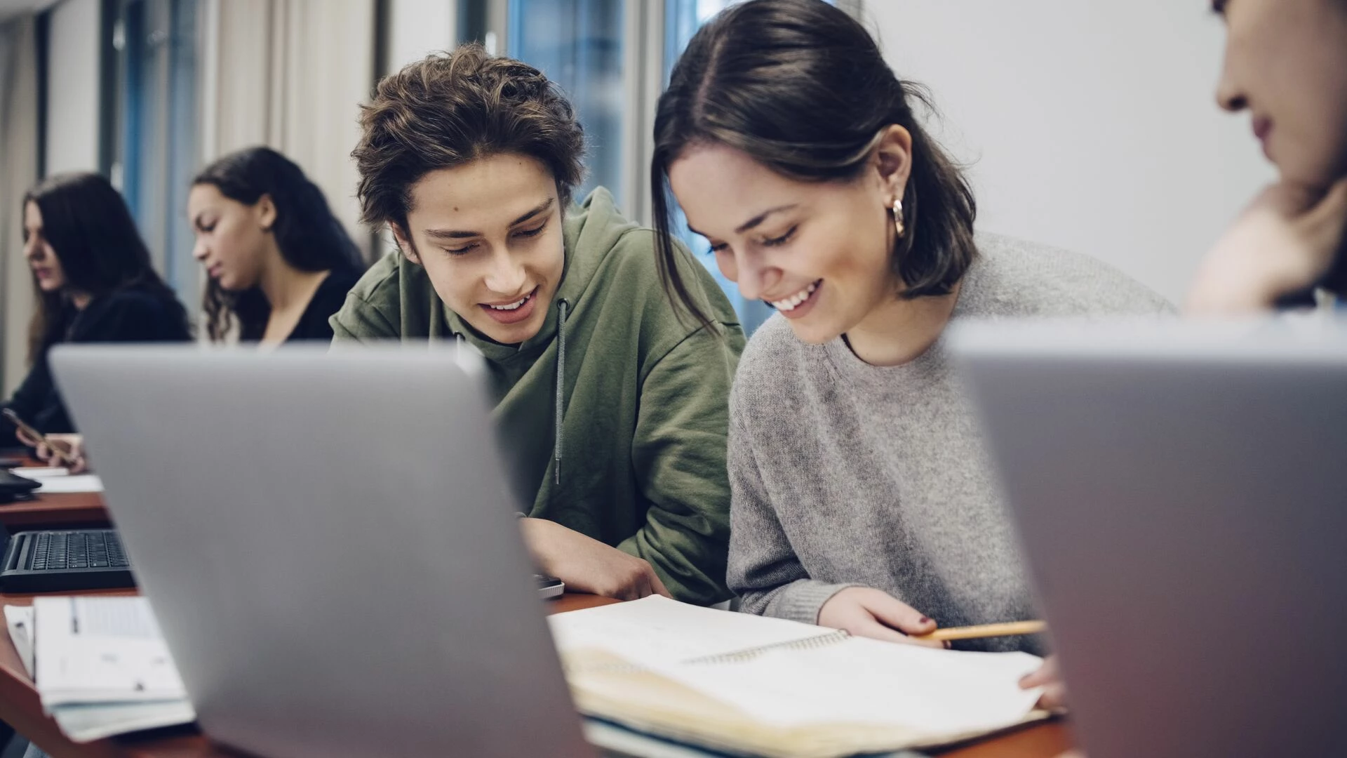 smiling-teenage-students-studying-at-desk-in-school