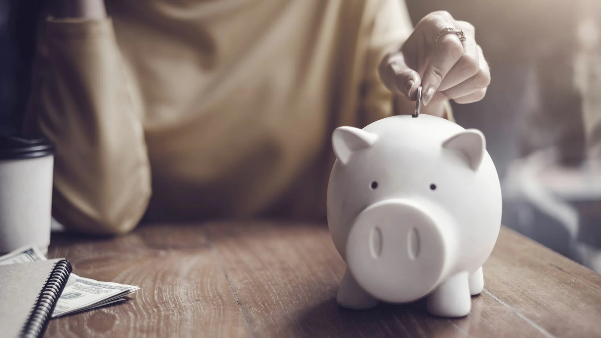 woman-putting-coin-in-piggy-bank