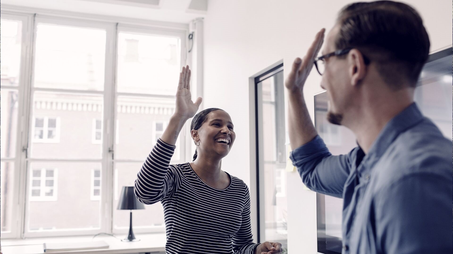 Two office workers giving a high five in celebration