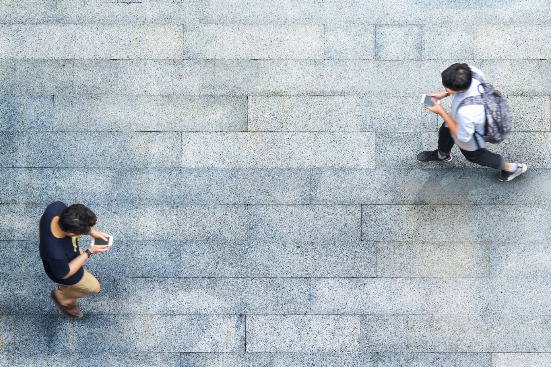 Two people walking and writing on their mobilephone