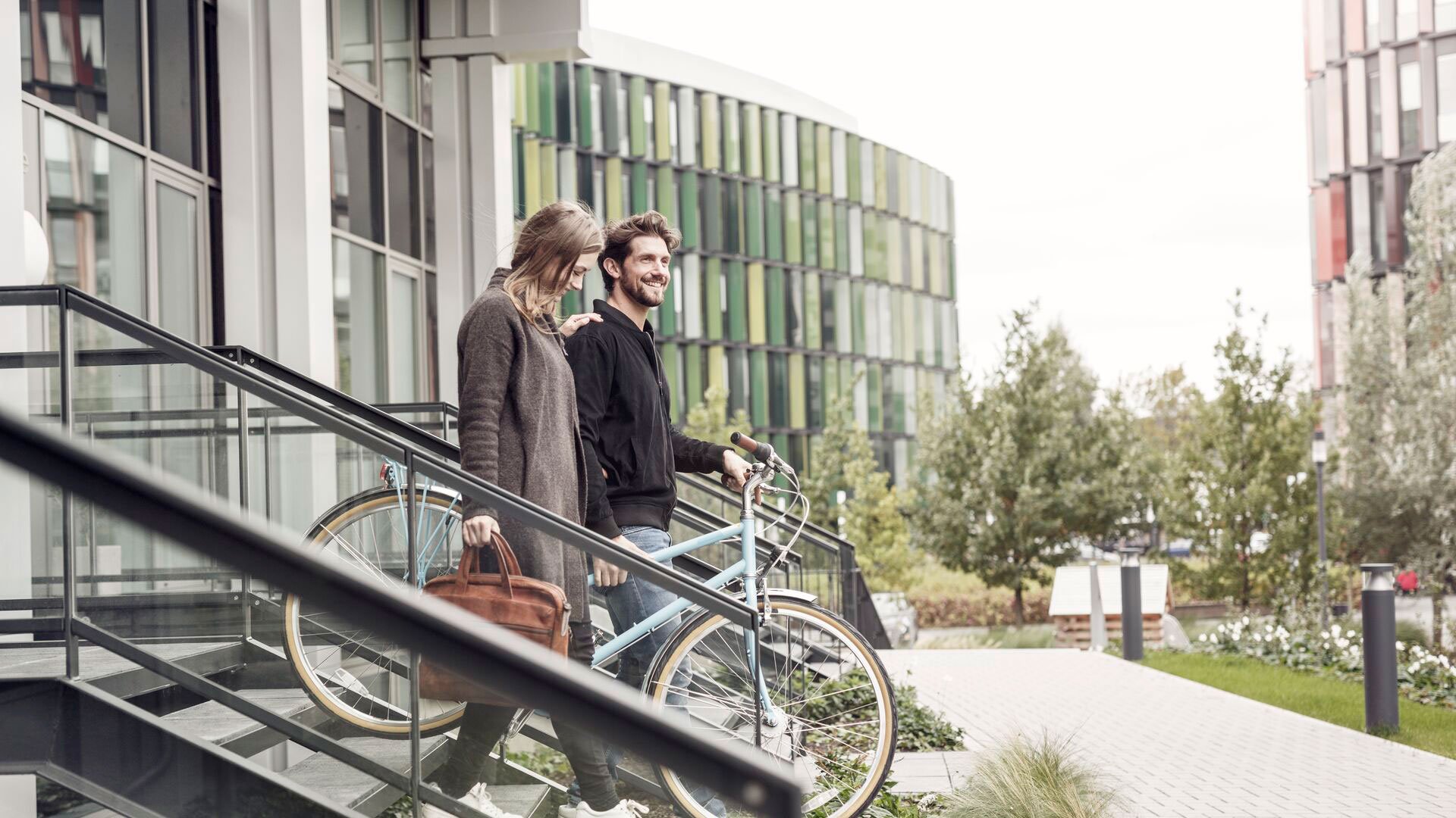 Smiling couple leaving building with bicycles
