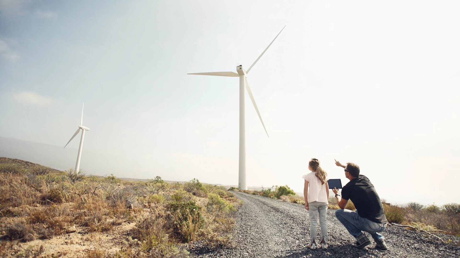 Man with young girl pointing at windmills