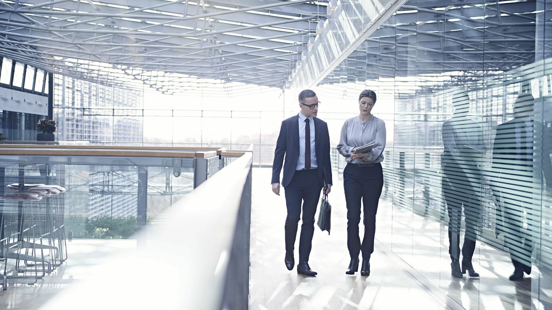Businessman and woman walking and talking on office balcony