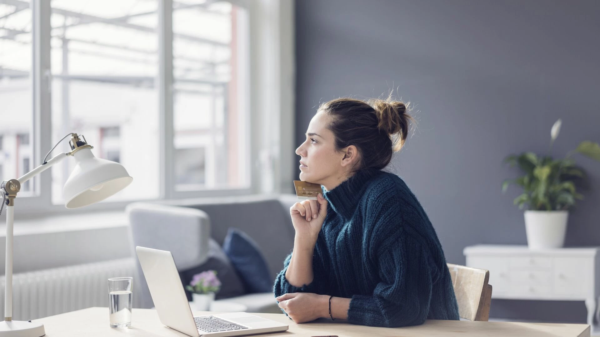 Profile of woman with laptop and credit card looking out the window
