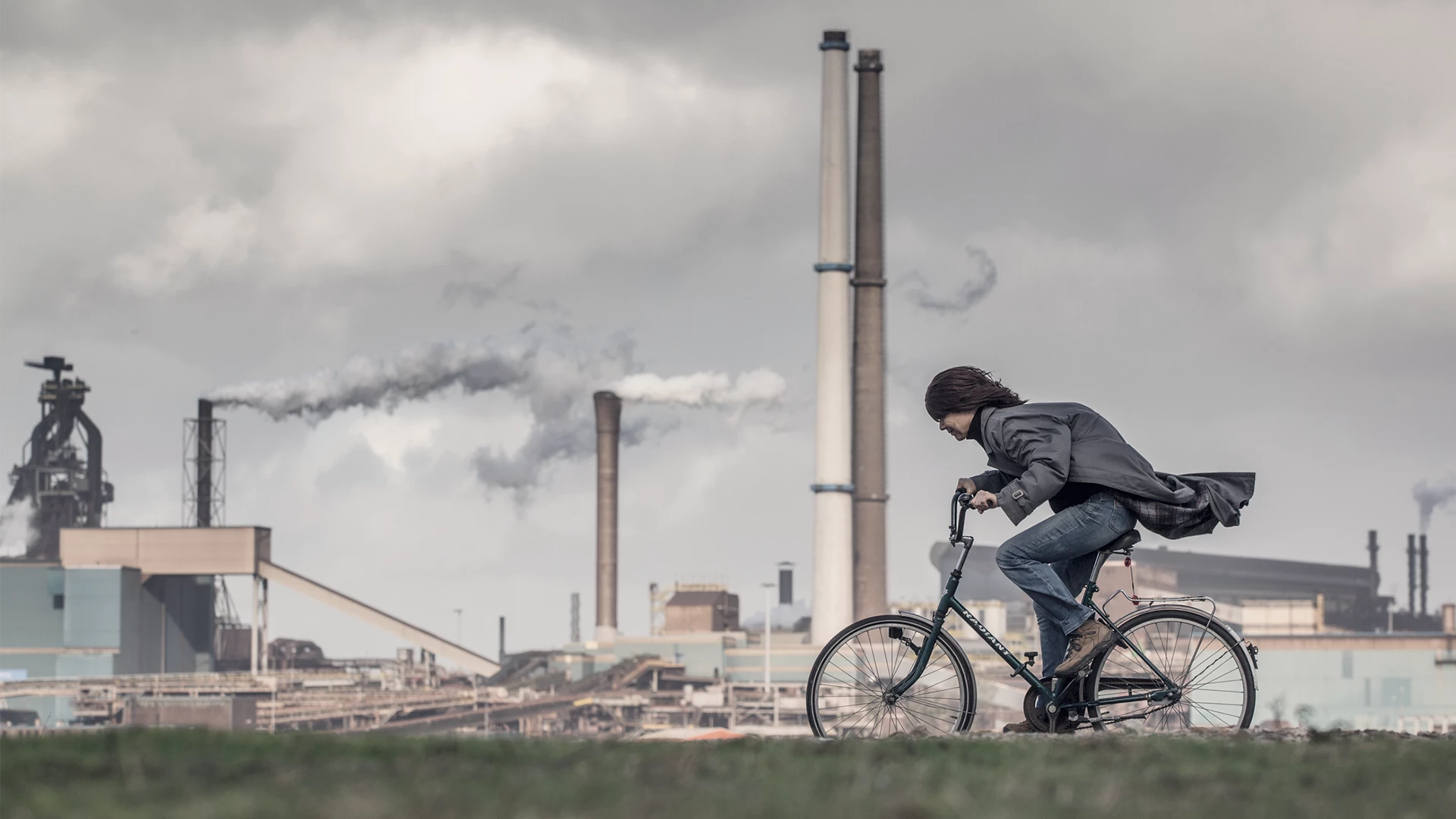 Person-riding-bike-in-front-of-factor