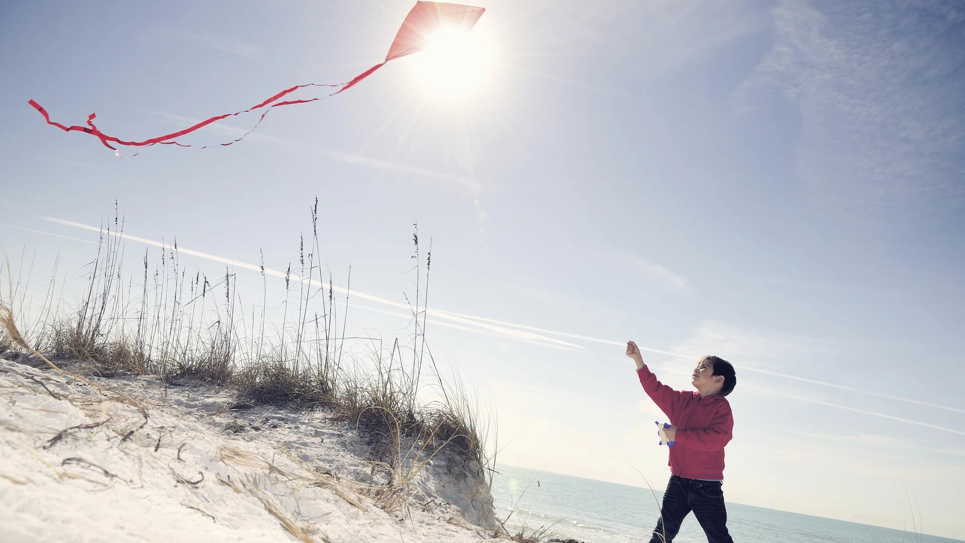 young-boy-flying-a-red-kite-on-beach