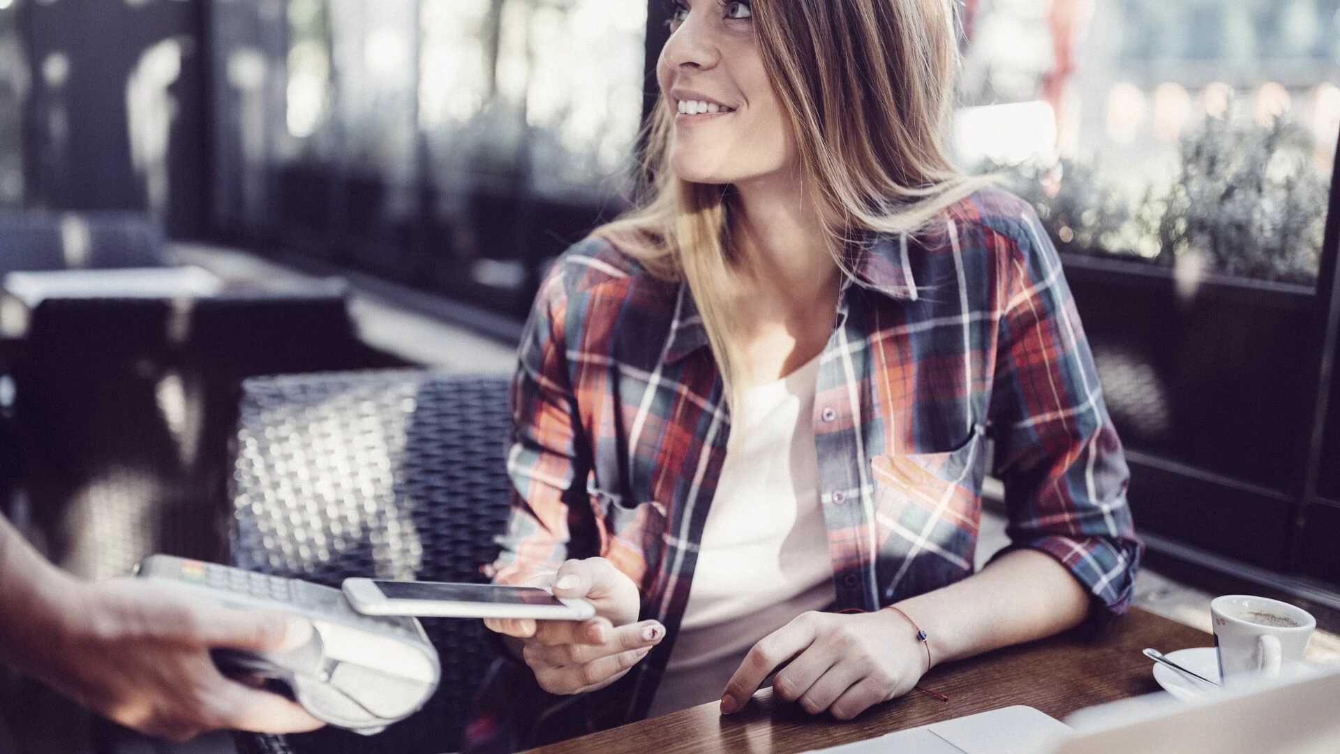 Customer in cafe paying contactless with smartphone