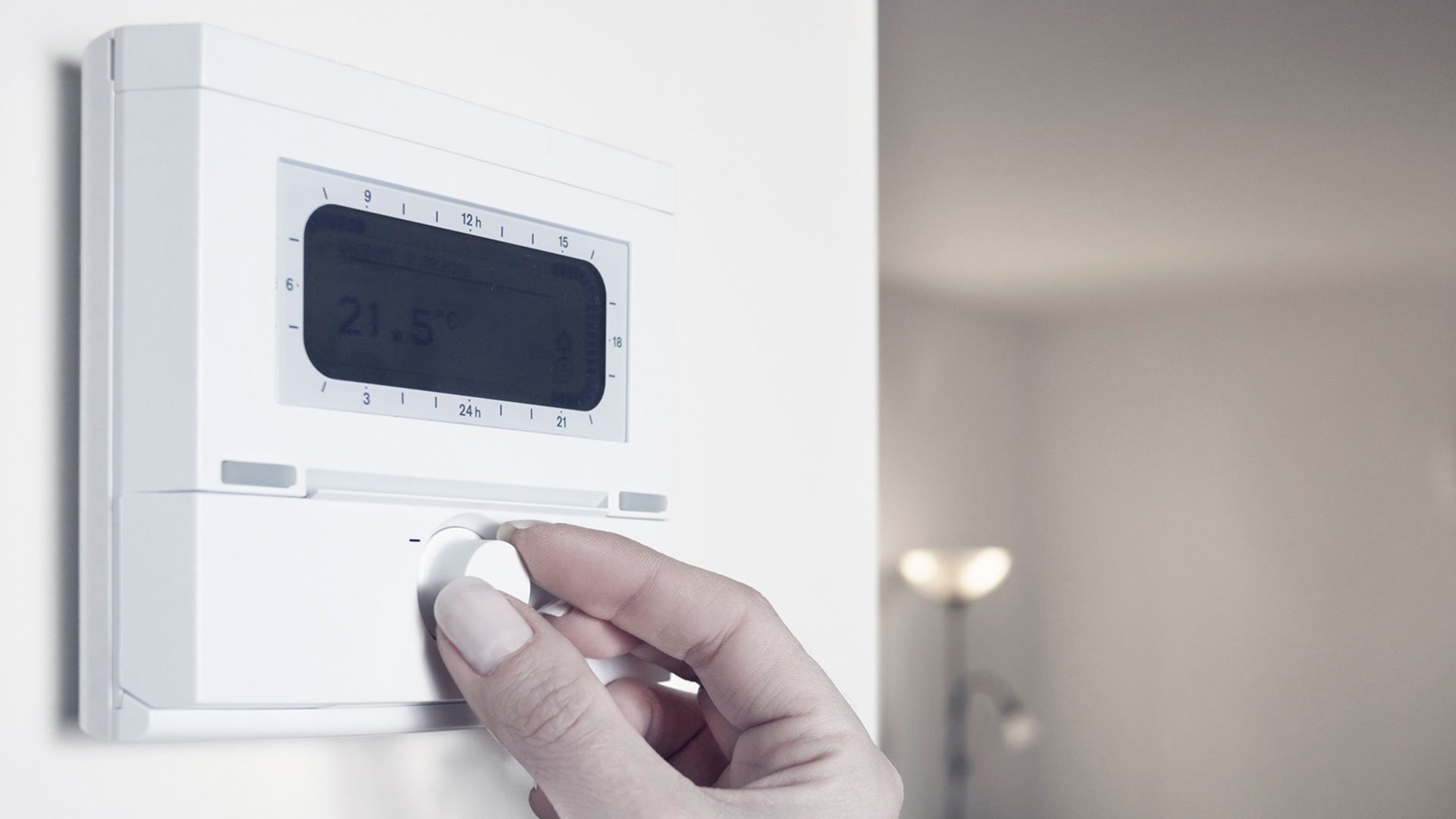 Close up of womans hand adjusting the thermostat