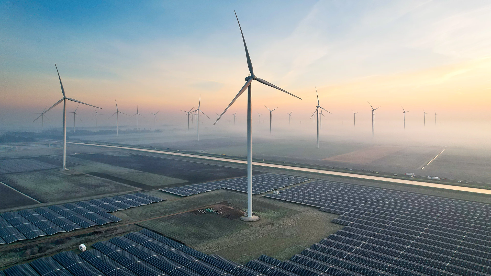 Solar energy field and wind turbines seen from the air during sunrise