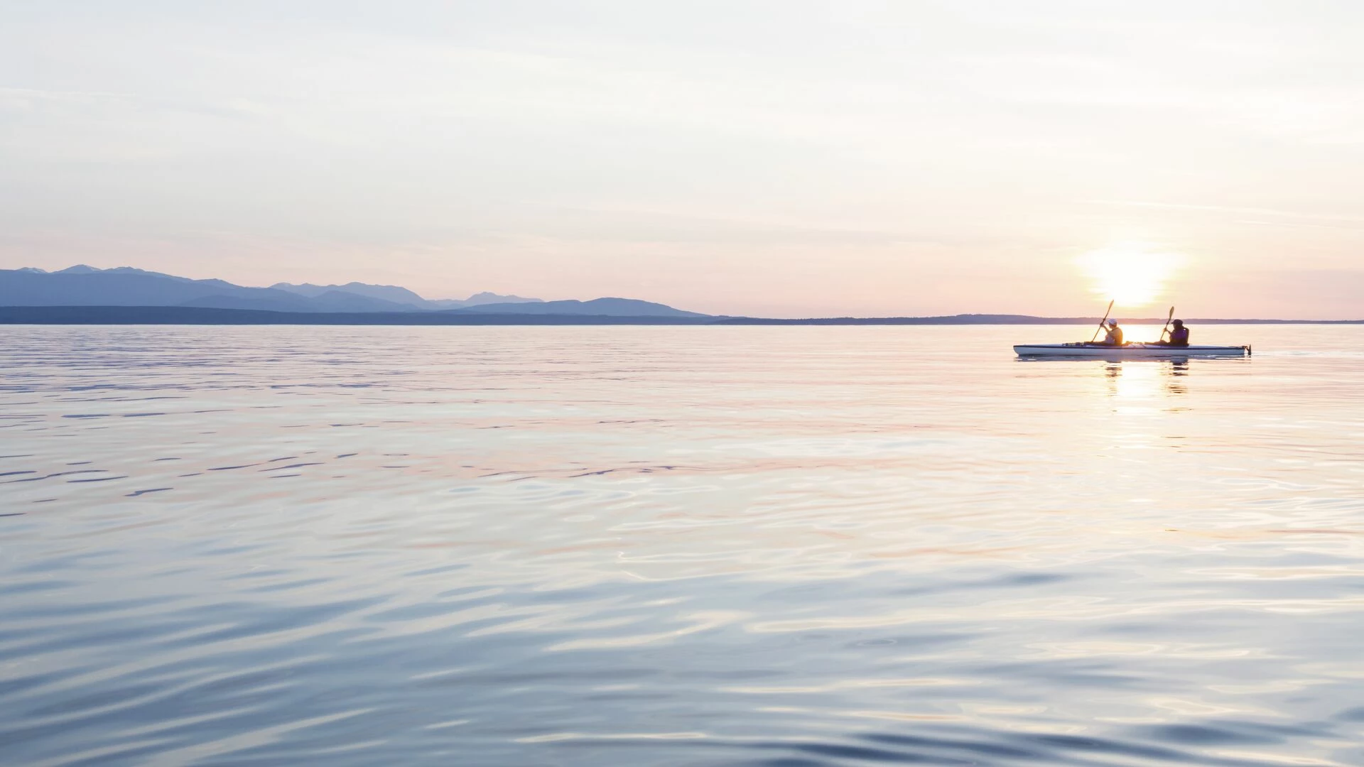 Two people kayaking together at sunset
