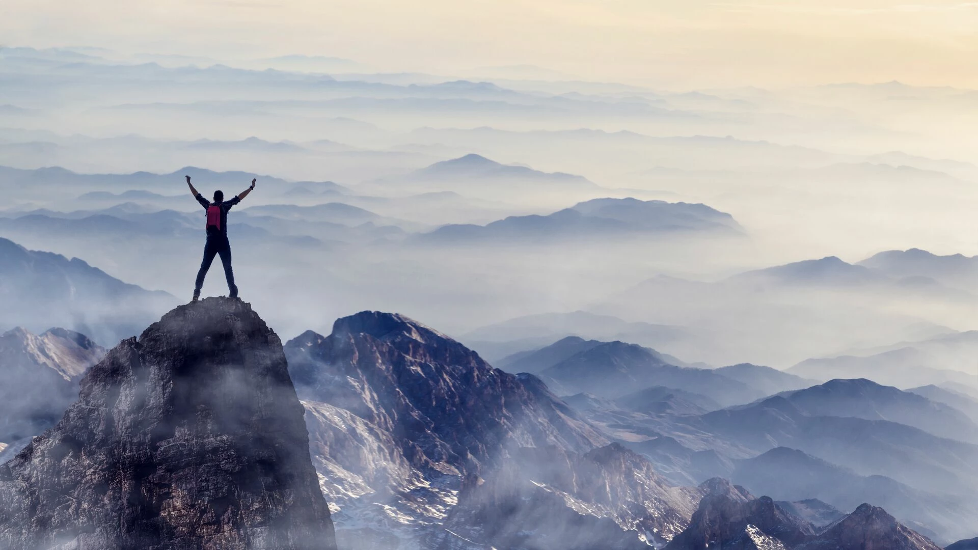 Young man enjoys success on top of a cliff