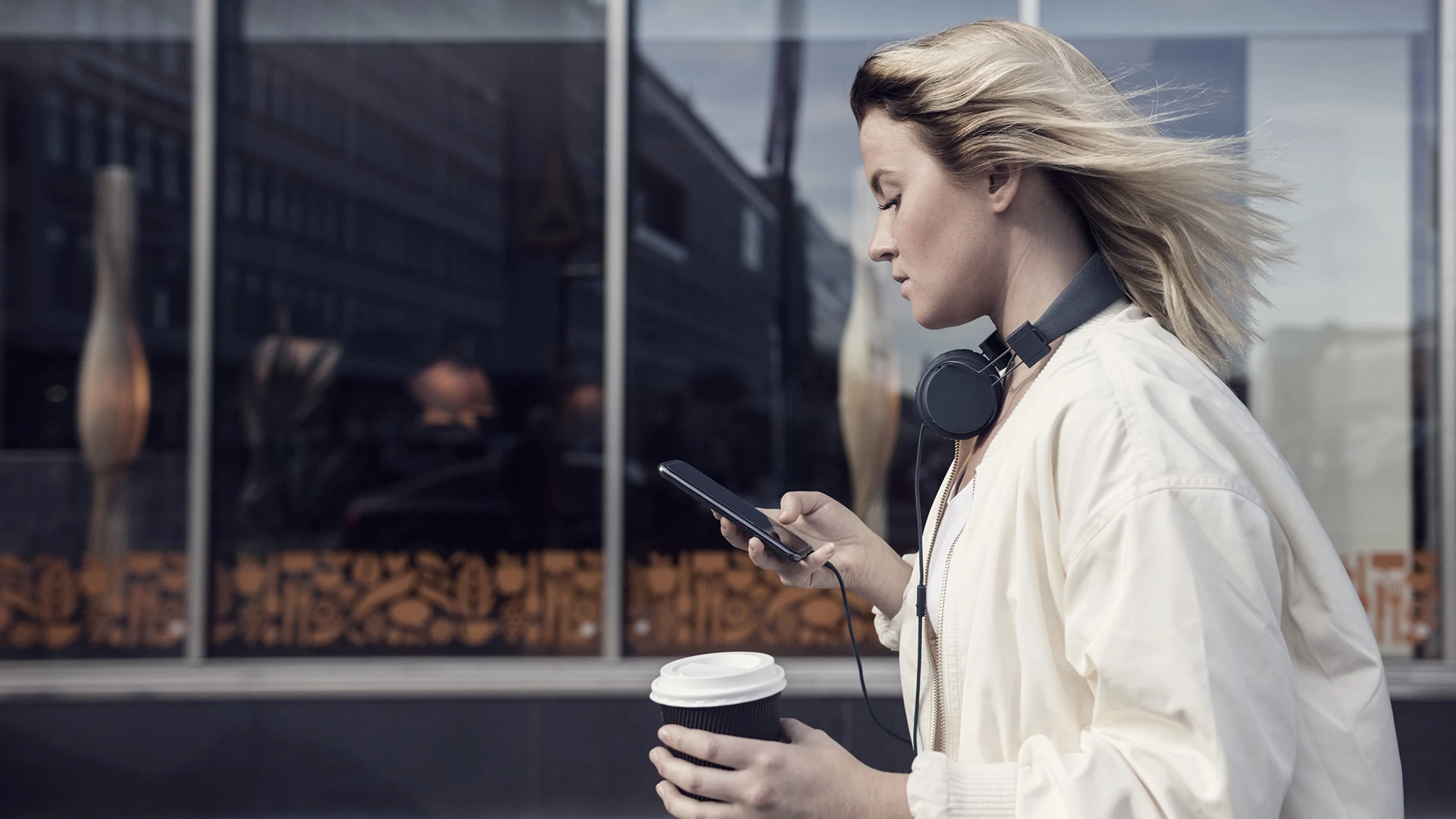 woman-using-mobile-phone-while-holding-disposable-cup.