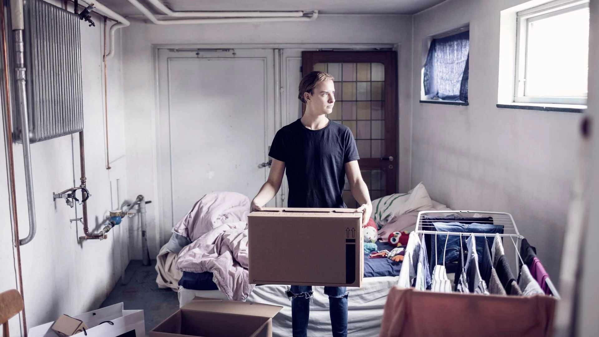 Man carrying cardboard box while standing in bedroom