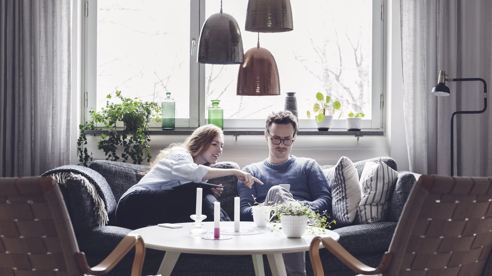 Couple using technologies while sitting on sofa