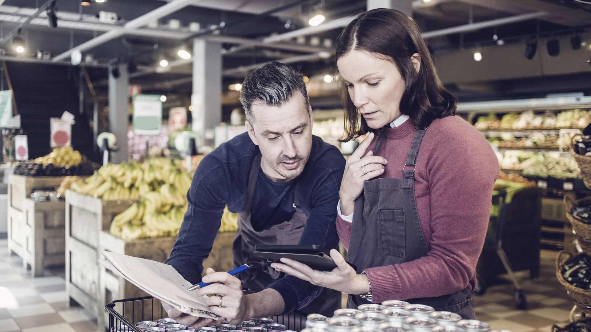 Store owners discussing over digital tablet by drink cans