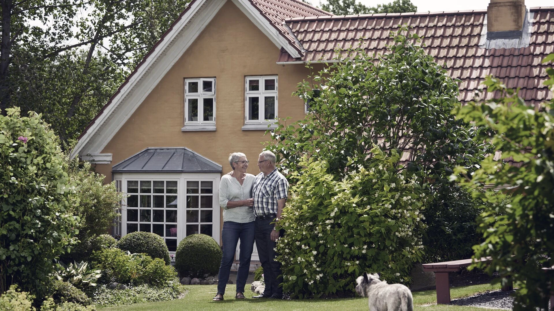 Pensionerat par vid gult hus