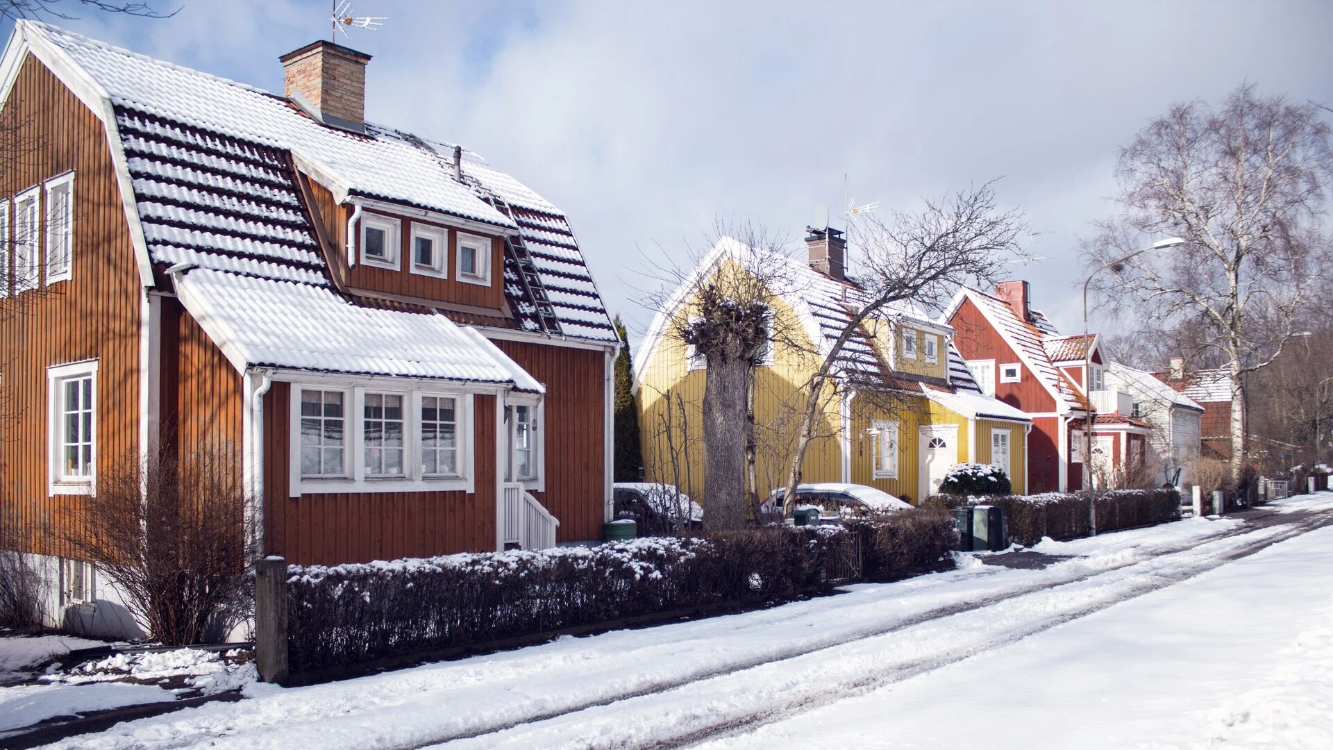 Lumisen kadun varrella pn punaisia ja keltaisia puisia omakotitaloja.