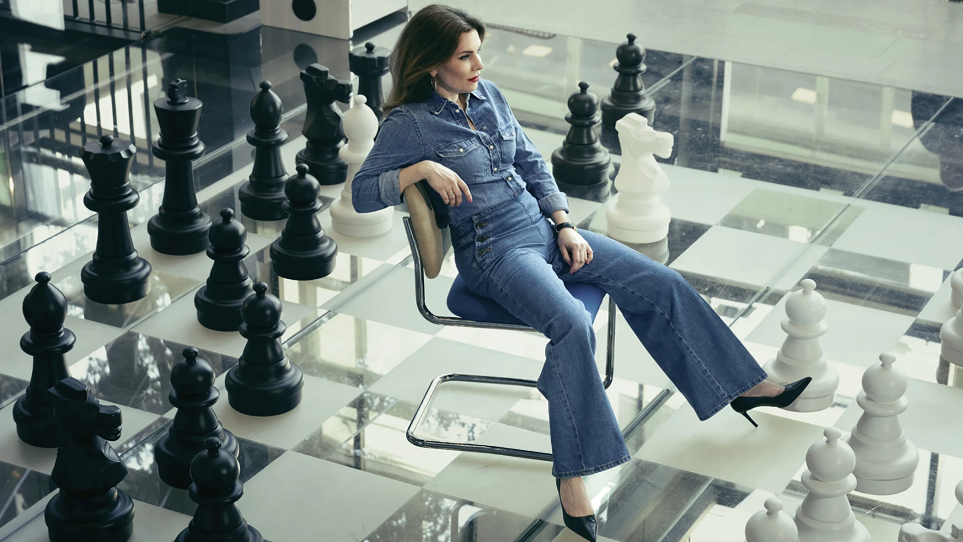 women sitting on a chair on a big chess board
