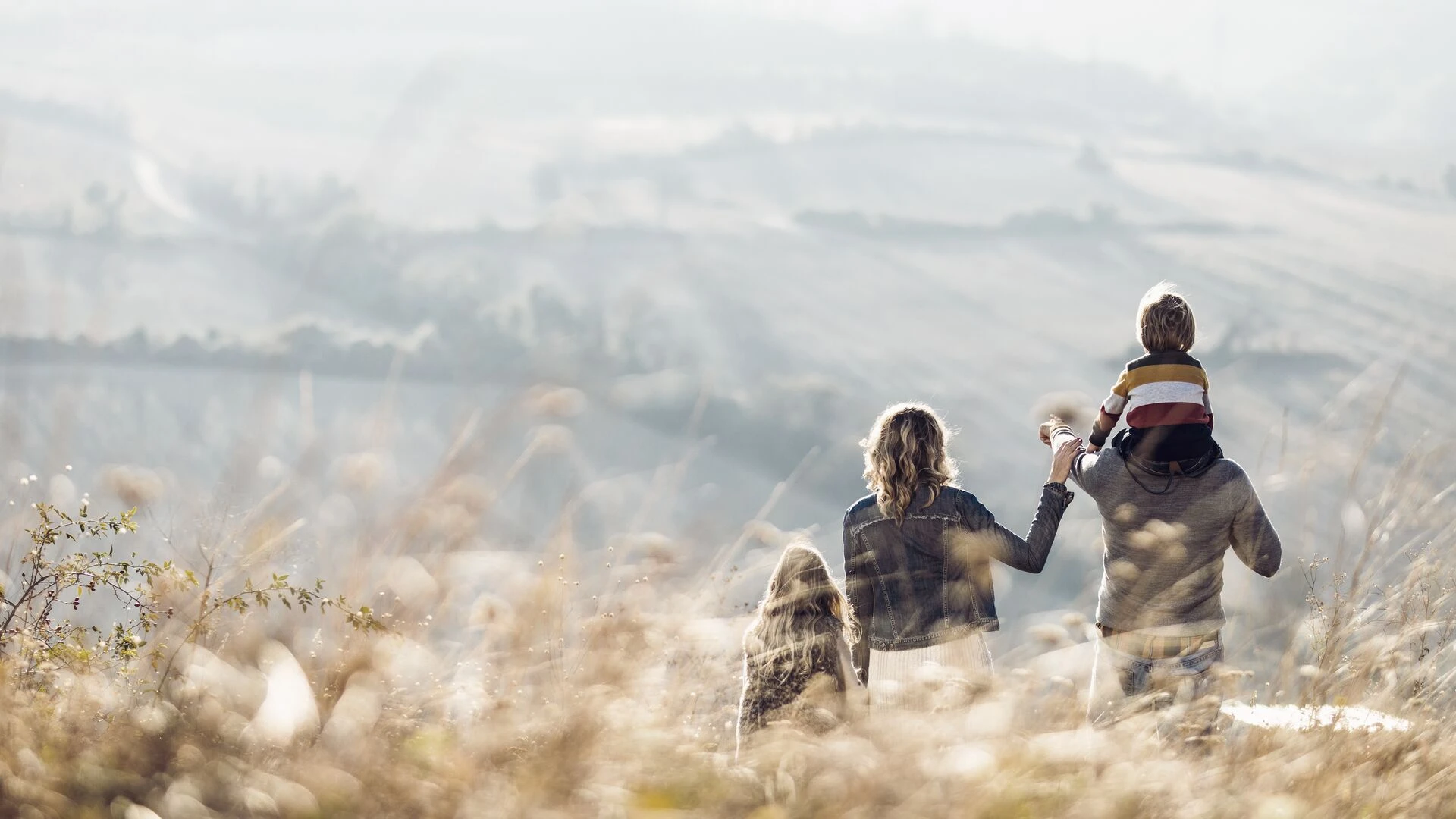 Rear view of a family standing on a hill in autumn day