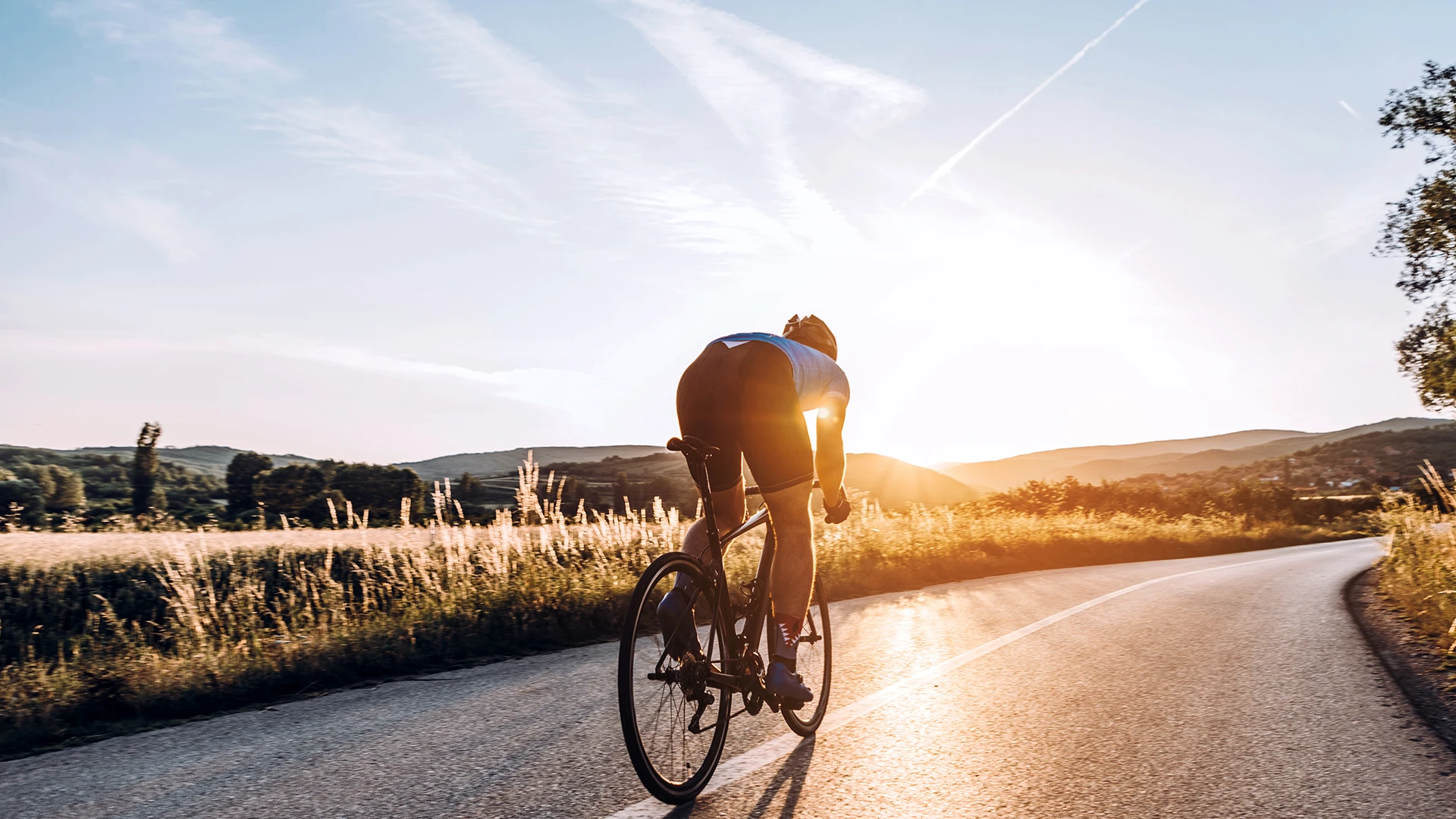 /Man%20on%20bike%20on%20rural%20road%20in%20sunset.