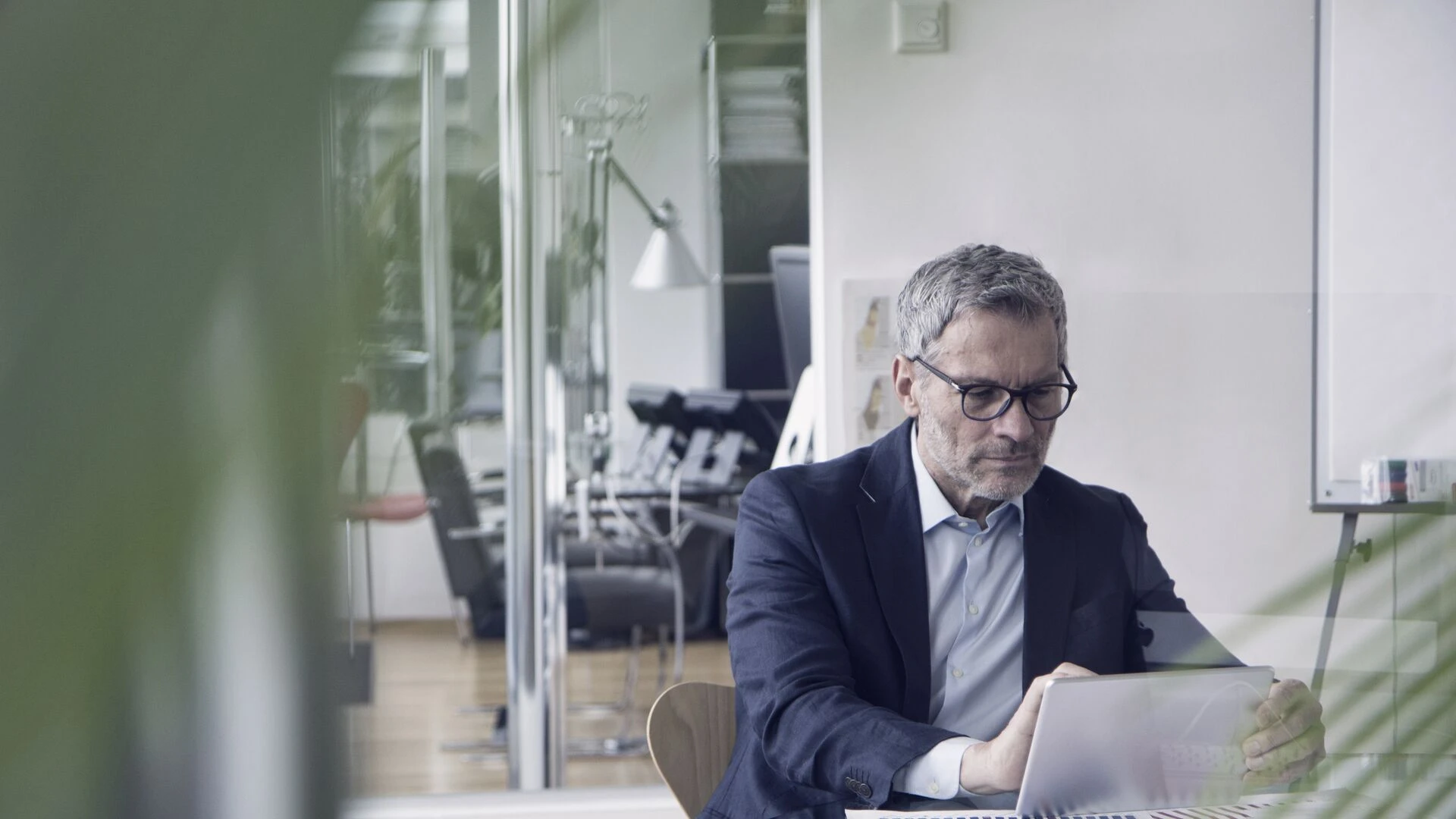 A businessman looking at a tablet screen in an office 