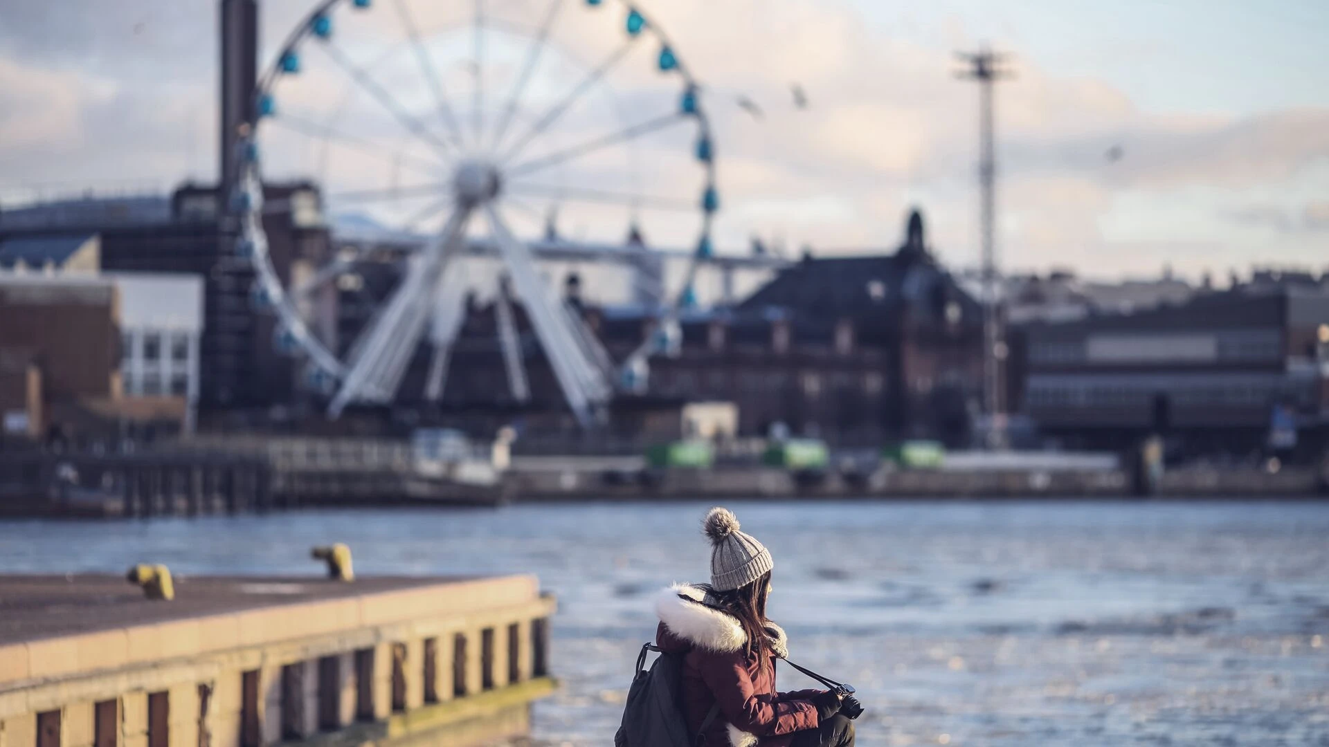 Young woman sitting in front of a skywheel in Helsinki 