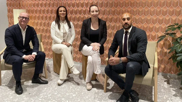 People in suites sitting in chairs looking into the camera. 