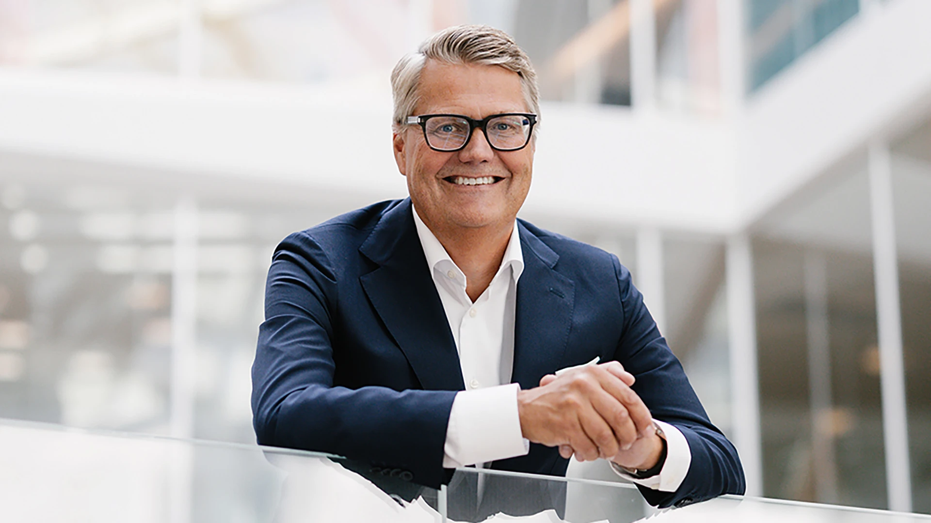 Man i kostym står i en trappa med glasräcken.