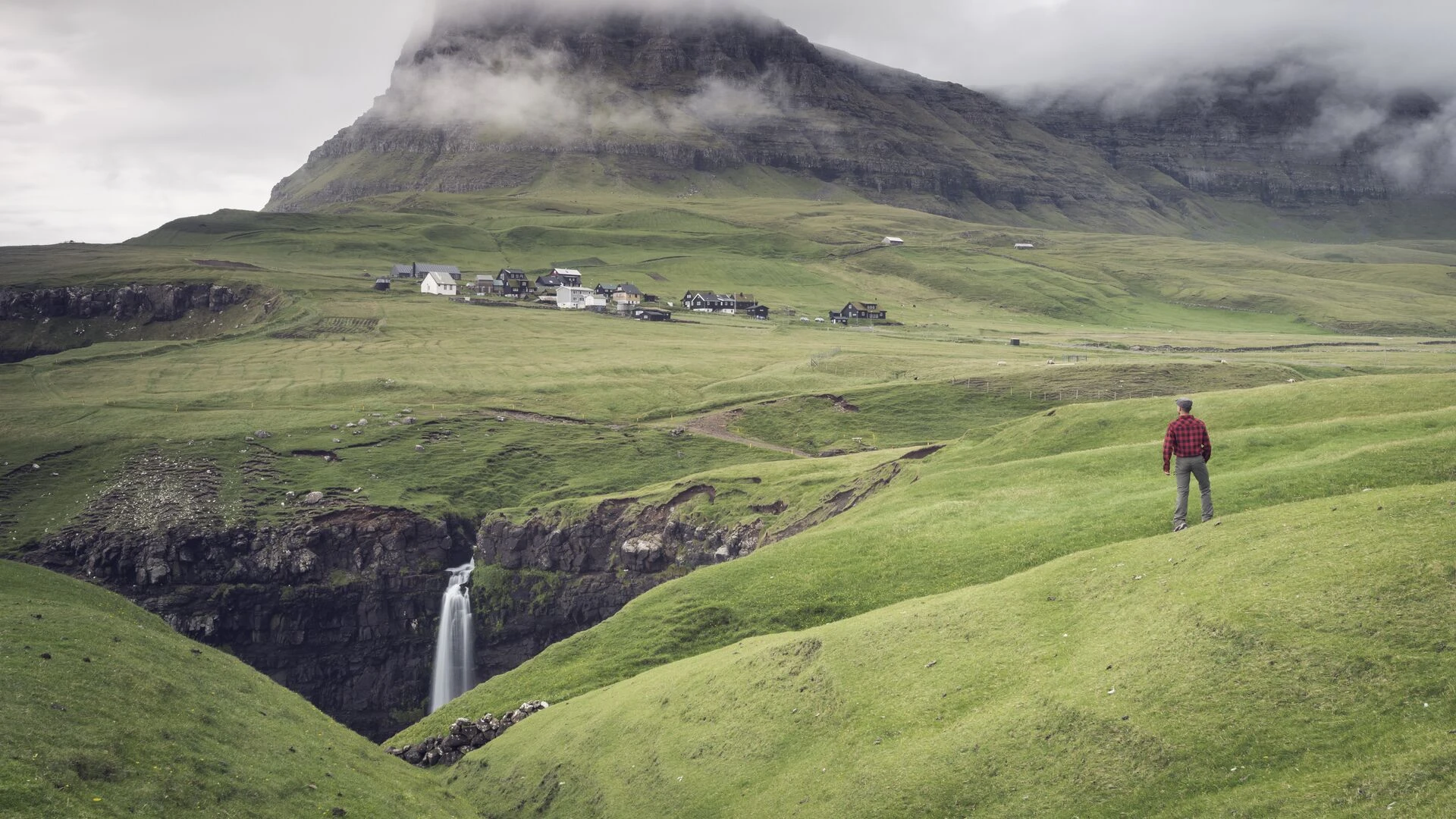 Man admires the little village of Gasadalur, Vagar Island, Faroe Islands, Denmark, Europe
