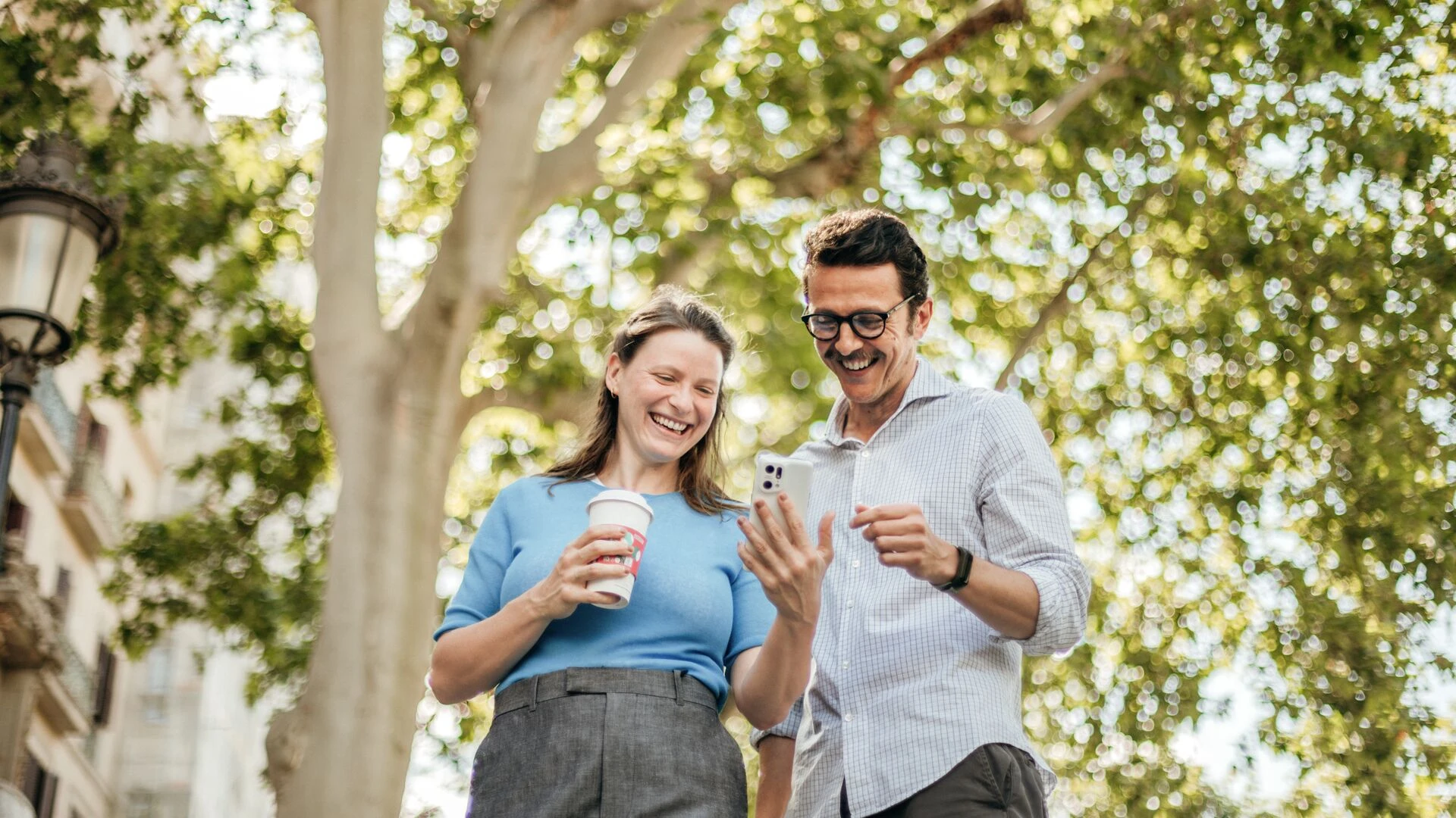 Woman and man checking phone outdoors. 