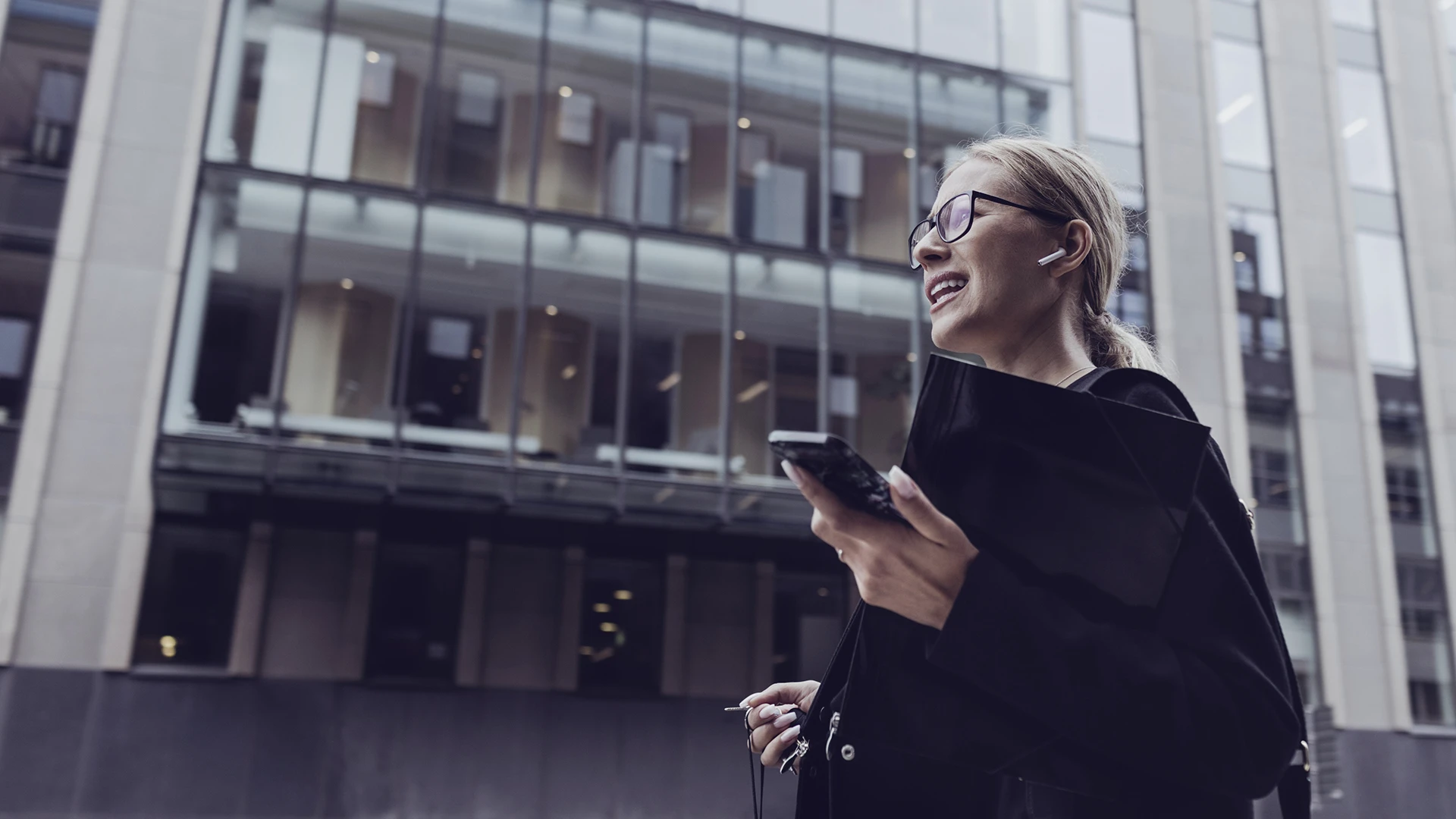 /businesswoman-talking-through-in-ear-headphones-in-city.