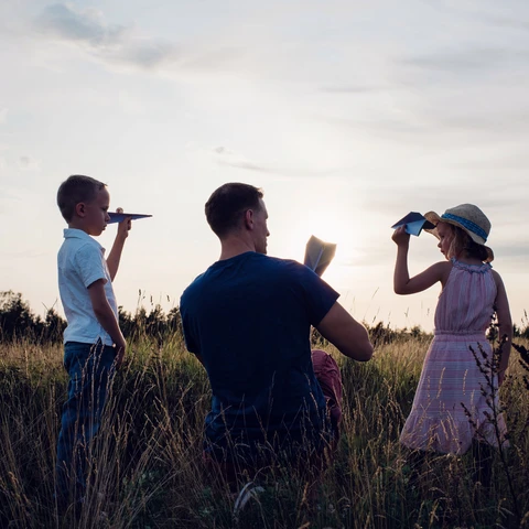 Father playing paper aeroplanes with his children