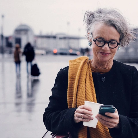 Senior woman outside smiling at phone