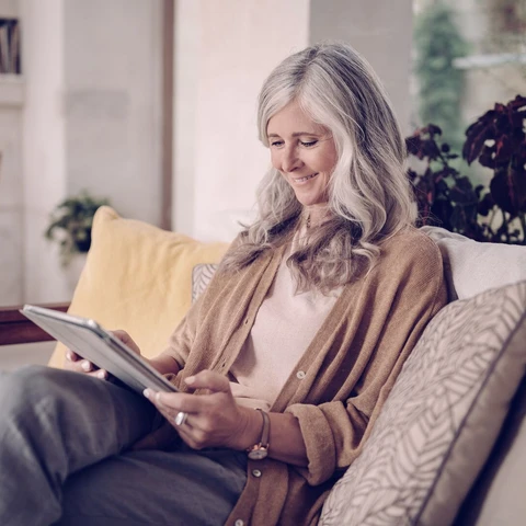 Senior woman sitting in couch with tablet