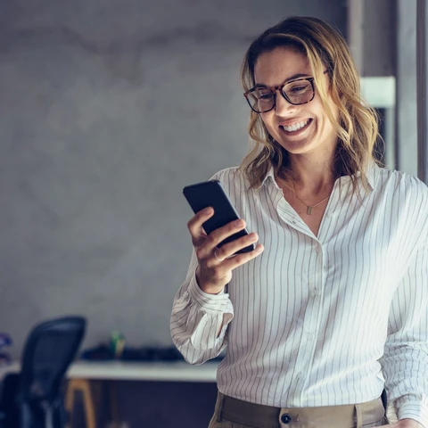 Smiling businesswoman using phone in office