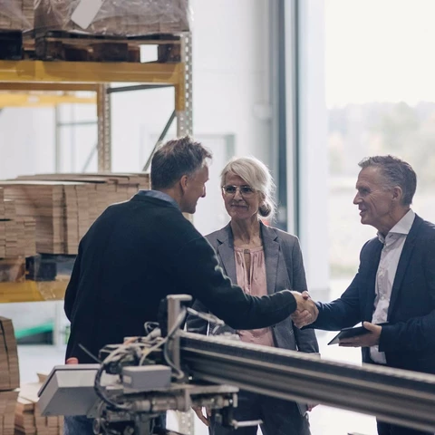 Three people shaking hands in a warehouse