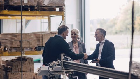 Three people shaking hands in a warehouse